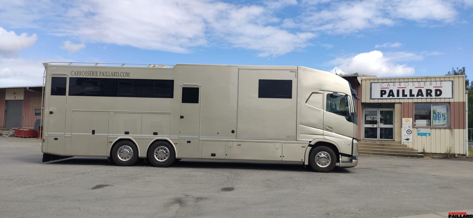 Camion-chevaux Volvo 6×2 beige stationné devant la Carrosserie Paillard